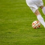 Fußballspiele mit Ball auf einem Fußballfeld.