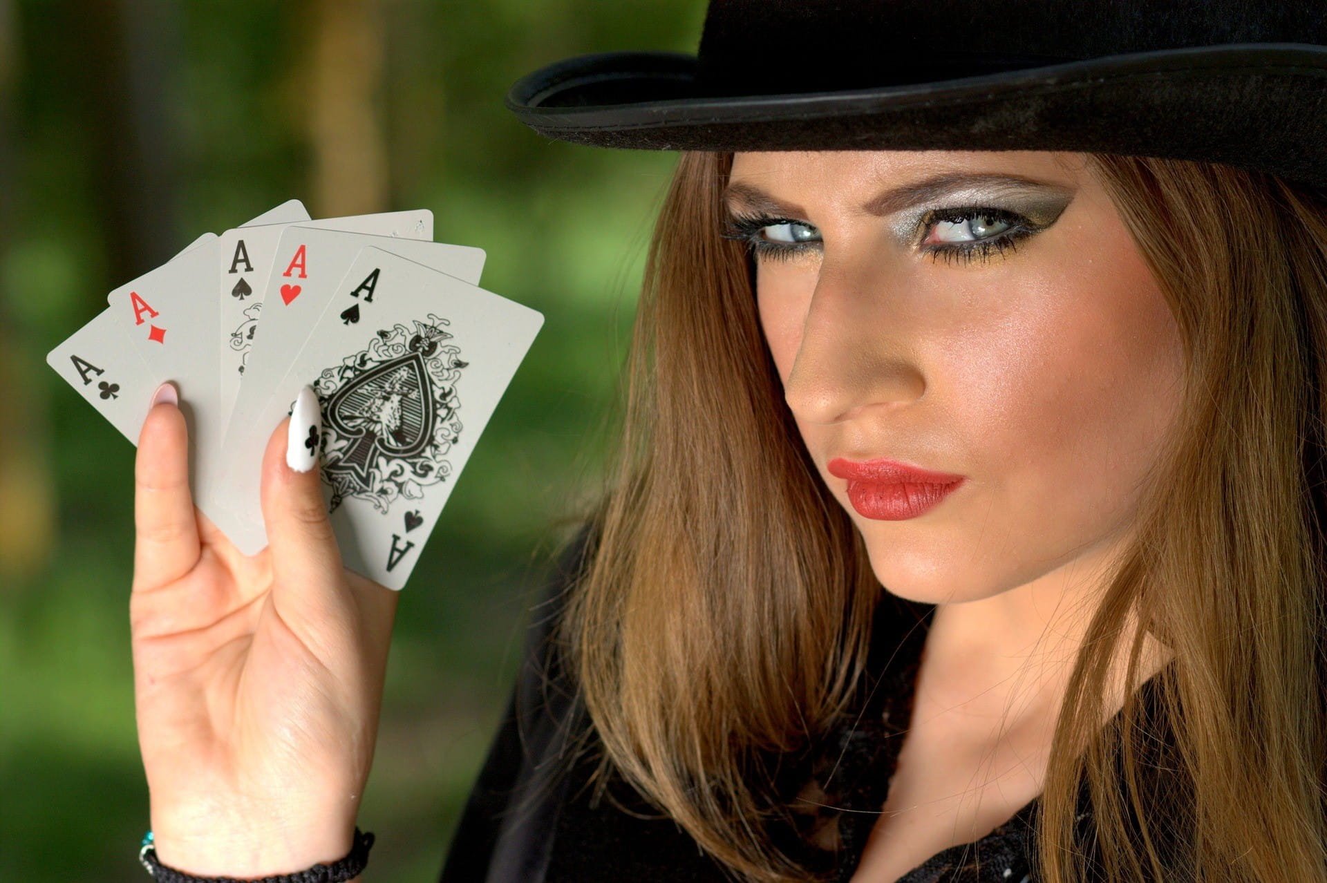 Eine junge Frau hält 5 ASS-Karten in der Hand.