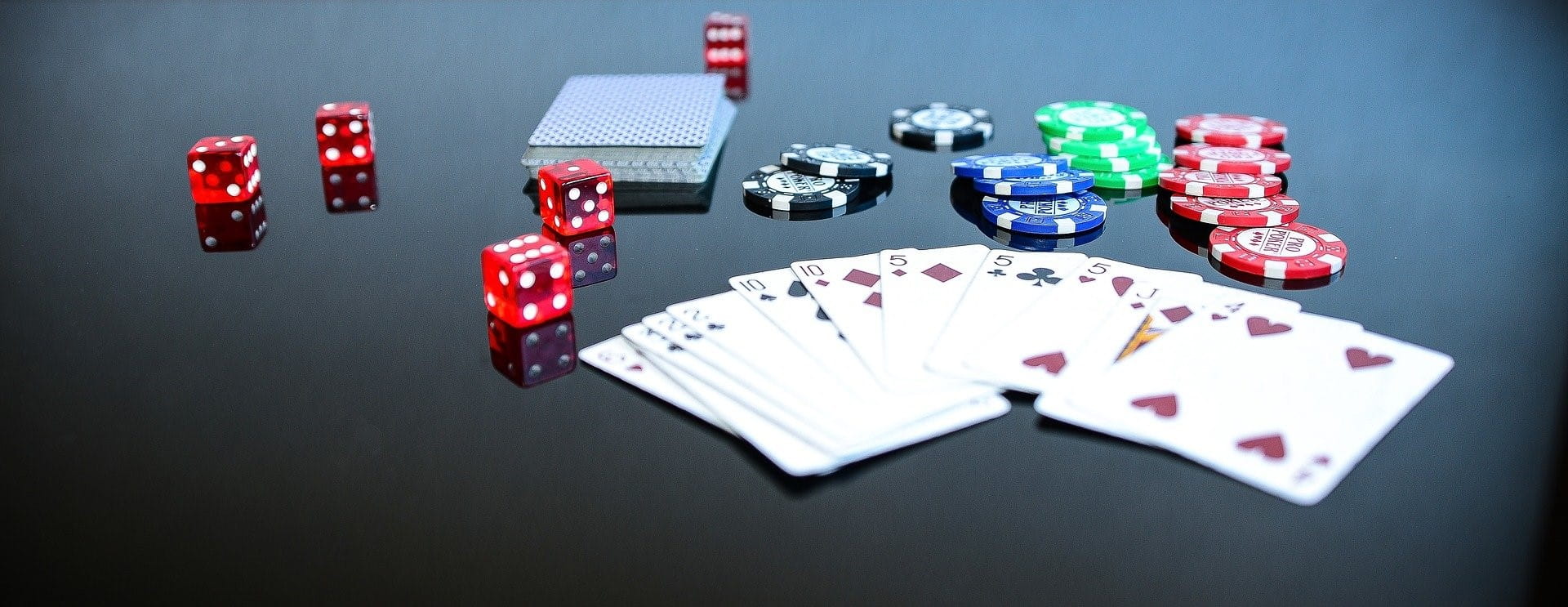 Pokerkarten, Würfel und Chips auf einem Spieltisch.