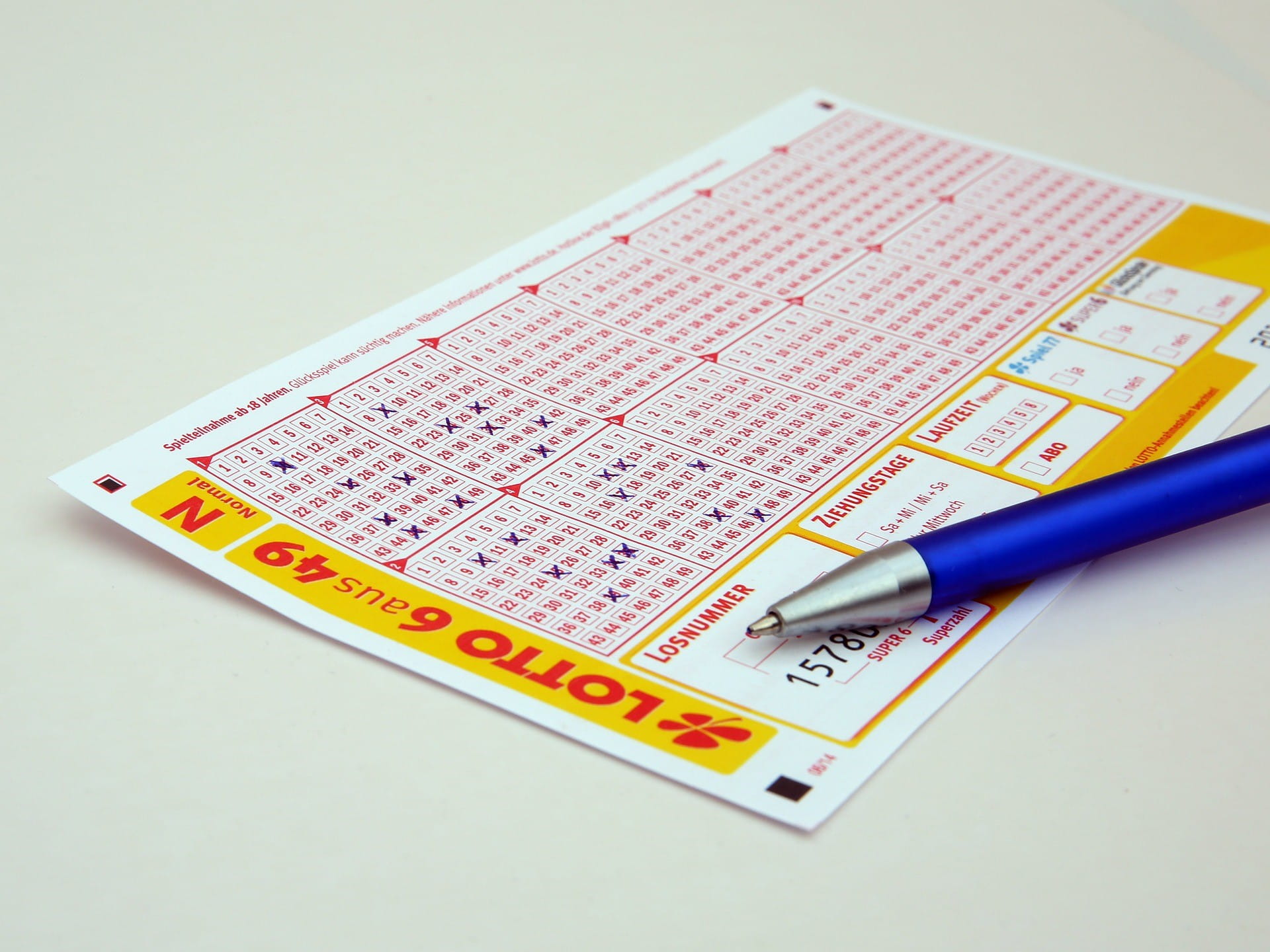 Ein Kugelschreiber liegt auf einem Lottoschein, bei dem vier Felder ausgefüllt wurden.