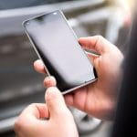 Mensch hält ausgeschaltetes iPhone in der Hand.
