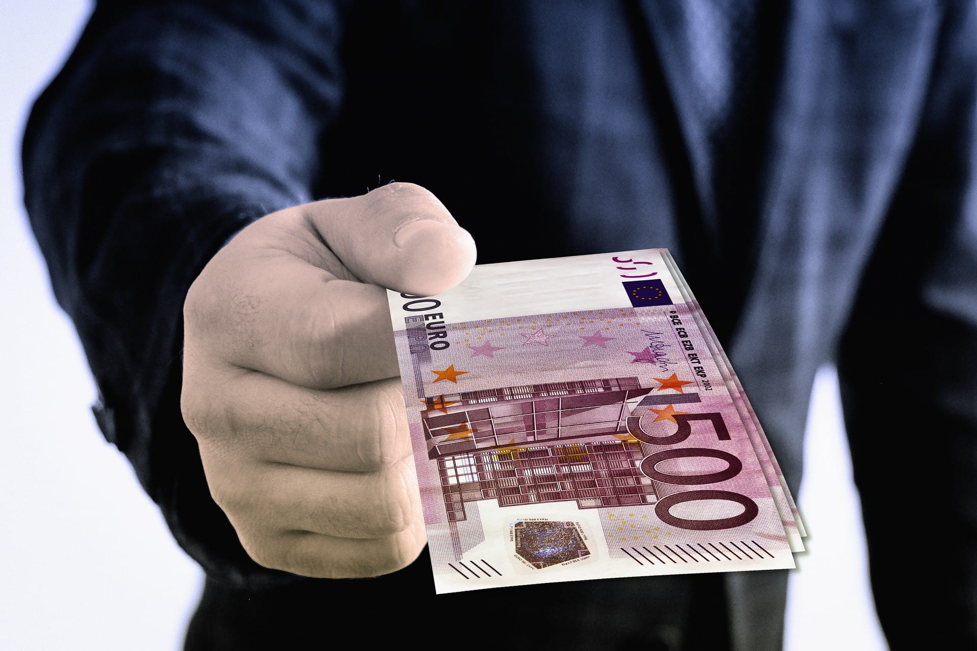 Eine Person hält mehrere 500-Euro-Scheine in der Hand.