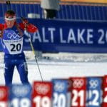 Ein Biathlon-Athlet beim Langlaufen vor einem Plakat mit der Aufschrift Salt Lake 2002.