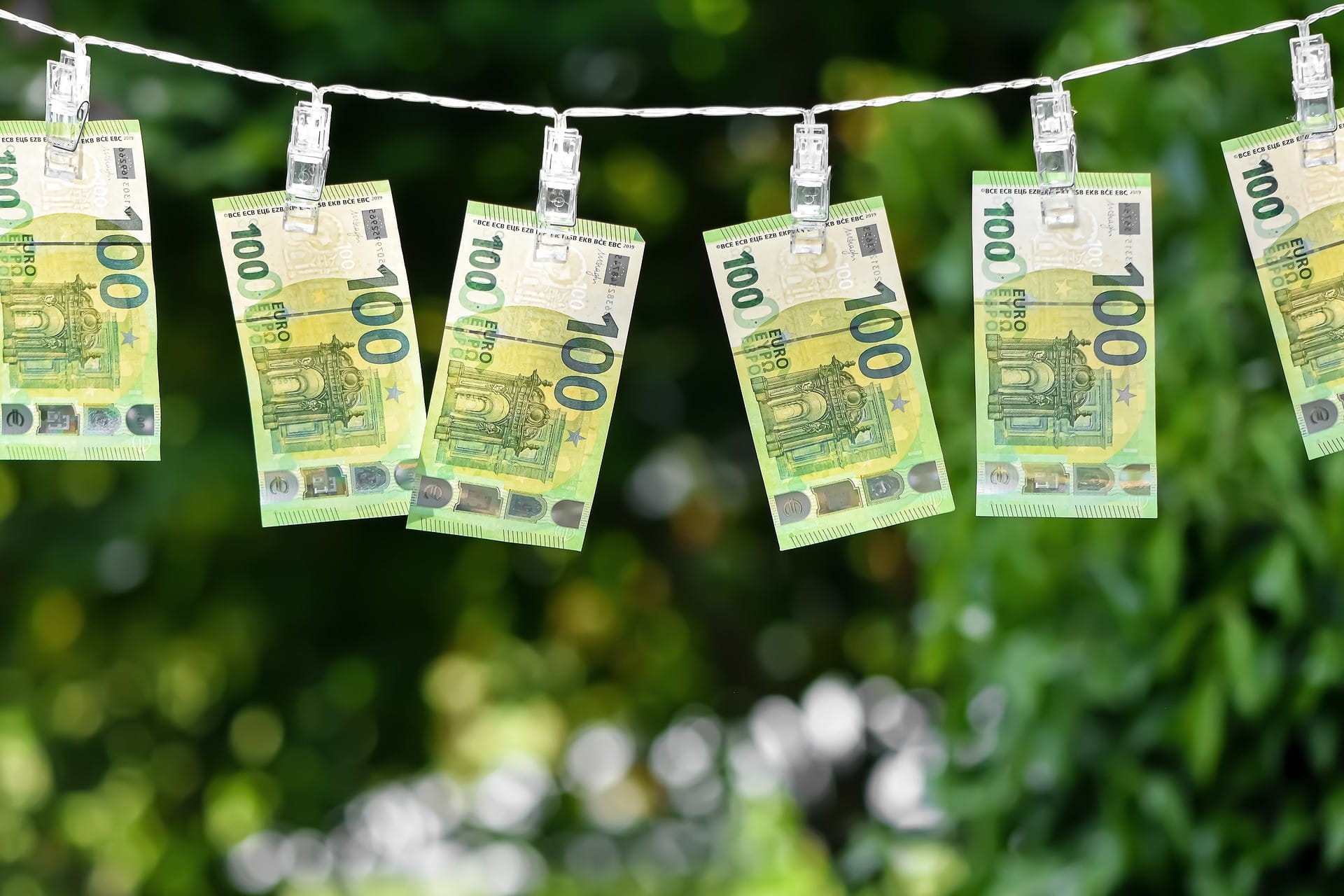 Sechs 100-Euro-Scheine hängen auf einer Wäscheleine zum Trocknen.