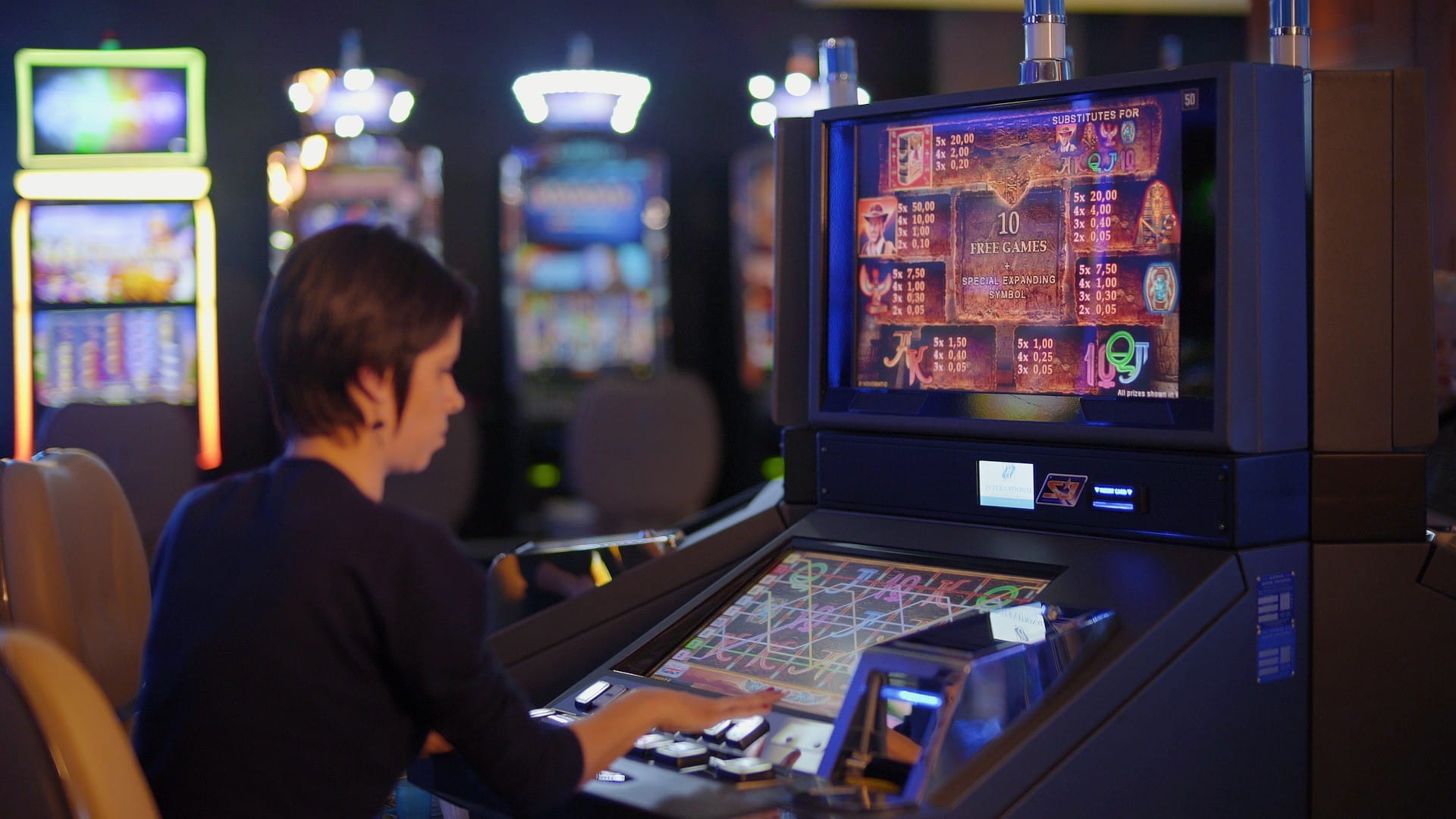 Eine Person spielt in einer Spielhalle an einem Automaten.