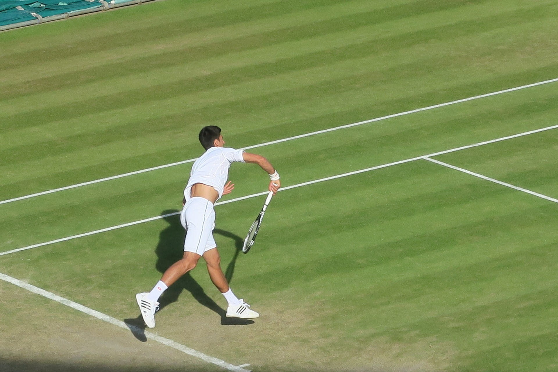 Ein männlicher Tennisspieler bewegt sich auf den Ball zu, der im Bild noch nicht sichtbar ist.