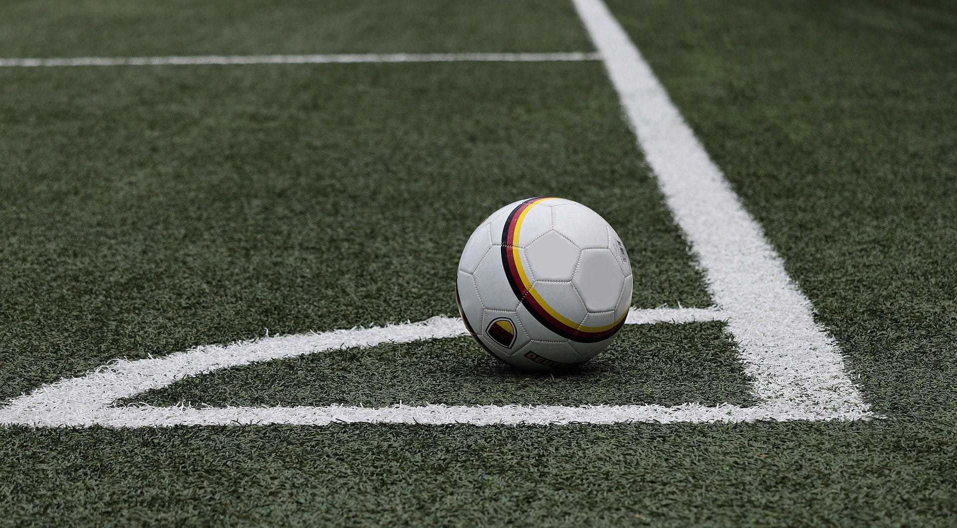 Ein Fußball liegt im eingezeichneten Eck eines Fußballfeldes.