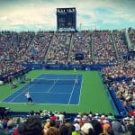 Ein vollbesetztes Stadion eines Tennisturniers – zwei Spieler sind gerade beim Spielen.