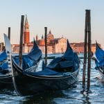 Im Hintergrund ist Venedig zu sehen – im Vordergrund stehen drei Gondeln auf dem Wasser.