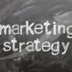 Auf einer Kreidetafel stehen die Worte Marketing Strategy.