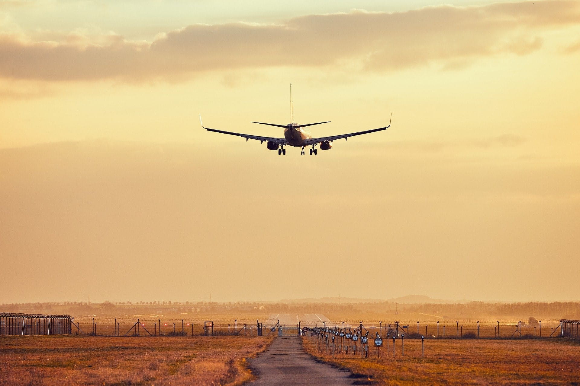 Ein Flugzeug im Landeanflug auf einen per Stacheldraht gesicherten Flughafen.
