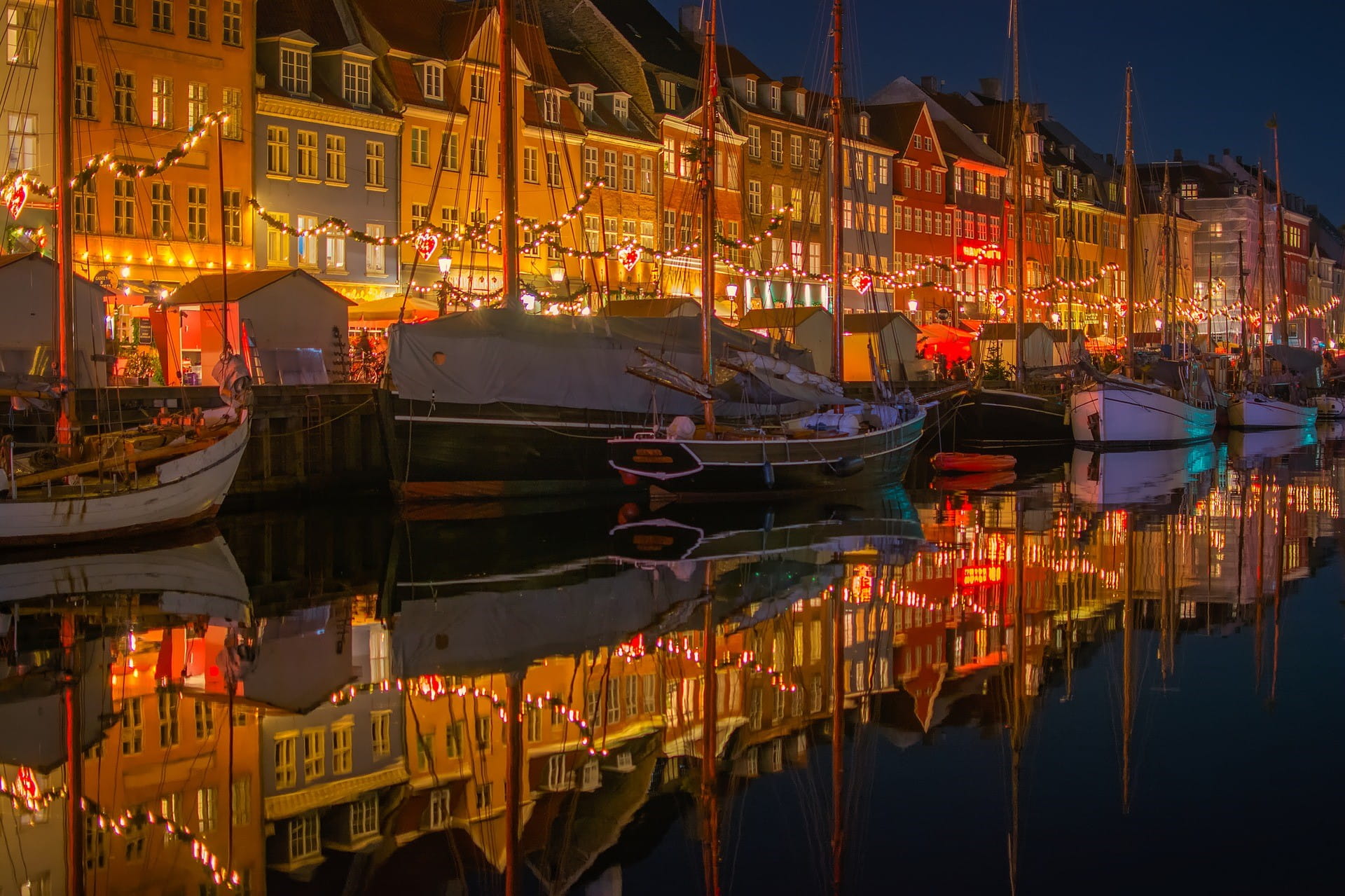 Eine dänische Stadt bei Nacht: vor den beleuchteten Häusern liegen kleine und mittelgroße Boote.