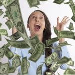 Eine Frau freut sich über einen Gewinn und wirft zahlreiche Dollarscheine in die Luft.