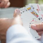 Zwei männliche Hände halten mehrere Pokerkarten in der Hand.