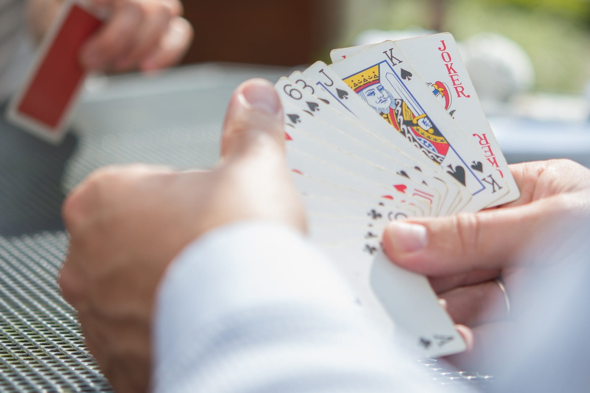 Zwei männliche Hände halten mehrere Pokerkarten in der Hand.