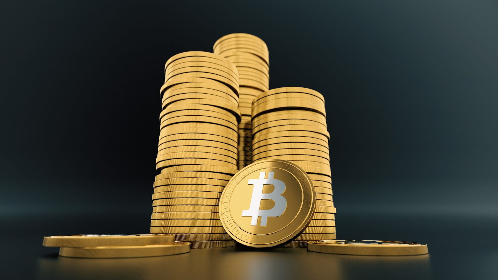 Auf einem Tisch stehen drei Stapel mit virtuellen Bitcoin-Münzen.