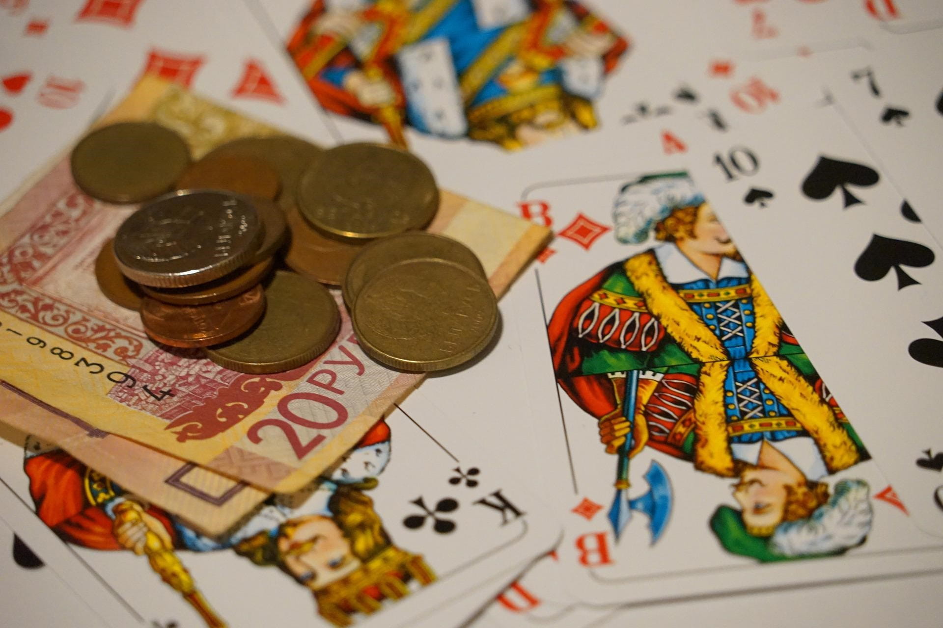 Auf Pokerkarten liegen Geldscheine und Münzen.