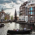 Durch die niederländische Hauptstadt Amsterdam fließt ein Fluss, der von vielen Booten genutzt wird.