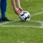Ein Fußballspieler setzt den Fußball wegen Eckball auf die richtige Position.
