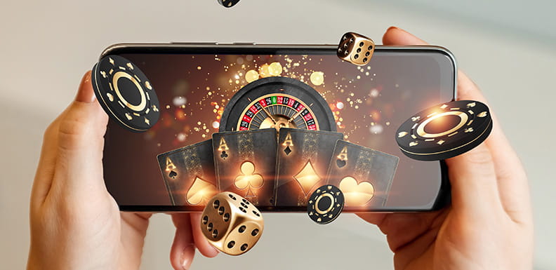 Ein Smartphone in zwei Händen gehalten, darauf ist ein Roulette-Kessel sowie Spielchips und Karten zu sehen.