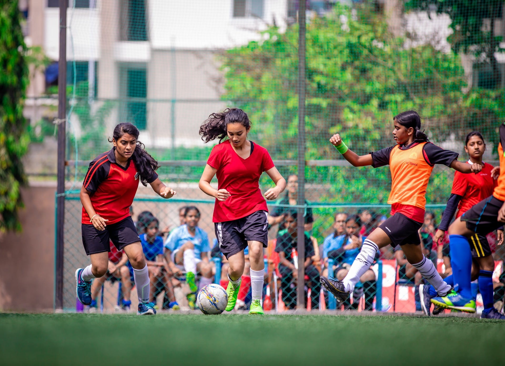 Drei Frauen stürmen gleichzeitig während eines Spiels auf den Fußball zu.