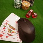 Fünf Pokerkarten und mehrere Spielchips unterschiedlicher Farben liegen auf einem Tisch.