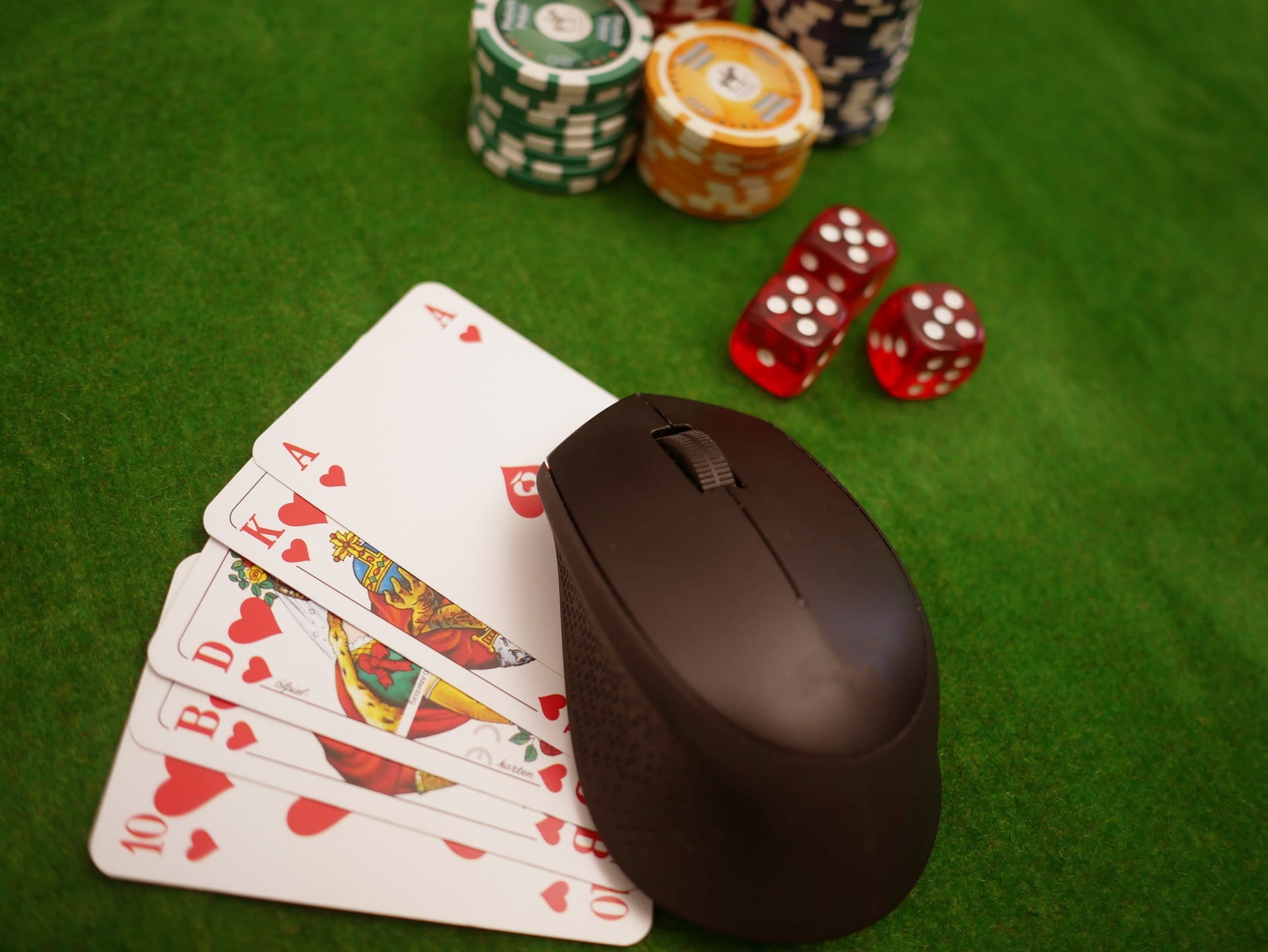 Lima kartu poker dan beberapa chip bermain dengan warna berbeda terletak di atas meja.