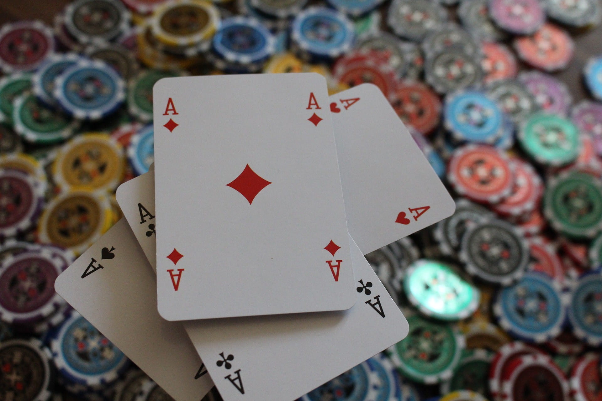 Ada empat kartu poker bersilang pada sejumlah besar chip permainan.