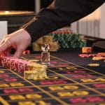 Ein Mann stapelt mehrere Spielchips auf einem Roulettetisch.