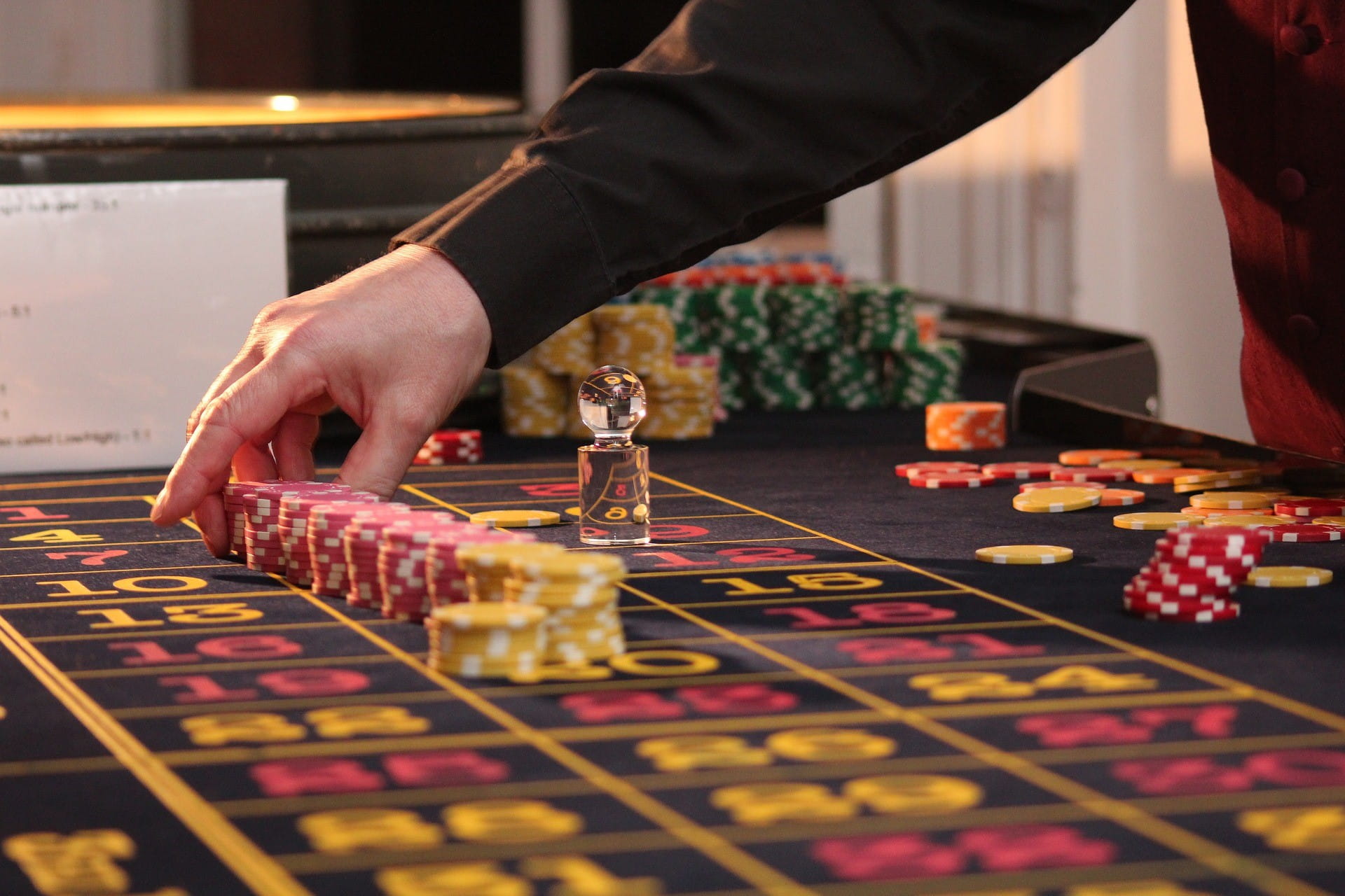 Seorang pria menumpuk beberapa chip permainan di atas meja rolet.