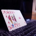 Fünf Pokerkarten stehen auf einem geöffnetem Laptop.