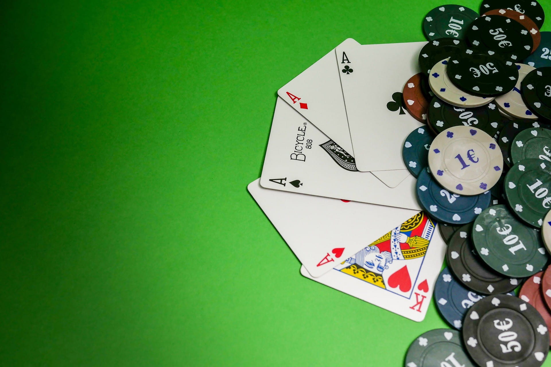 Ada banyak kartu remi dan token dalam berbagai denominasi euro di atas meja judi hijau.