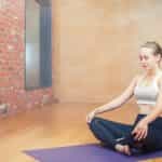 Eine Frau sitzt in der einfachen Yogaposition und meditiert.