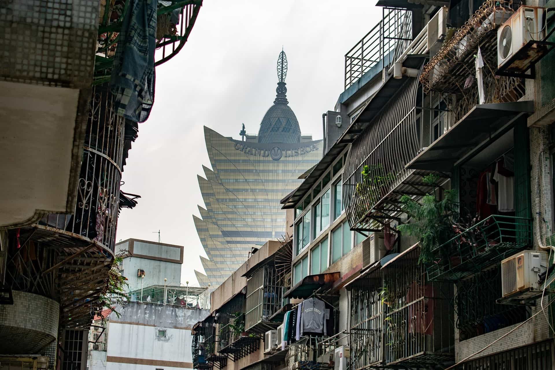 Hinter den kleineren Wohnhäusern ragt eines der berühmten Casinogebäude Macaus in den Himmel.