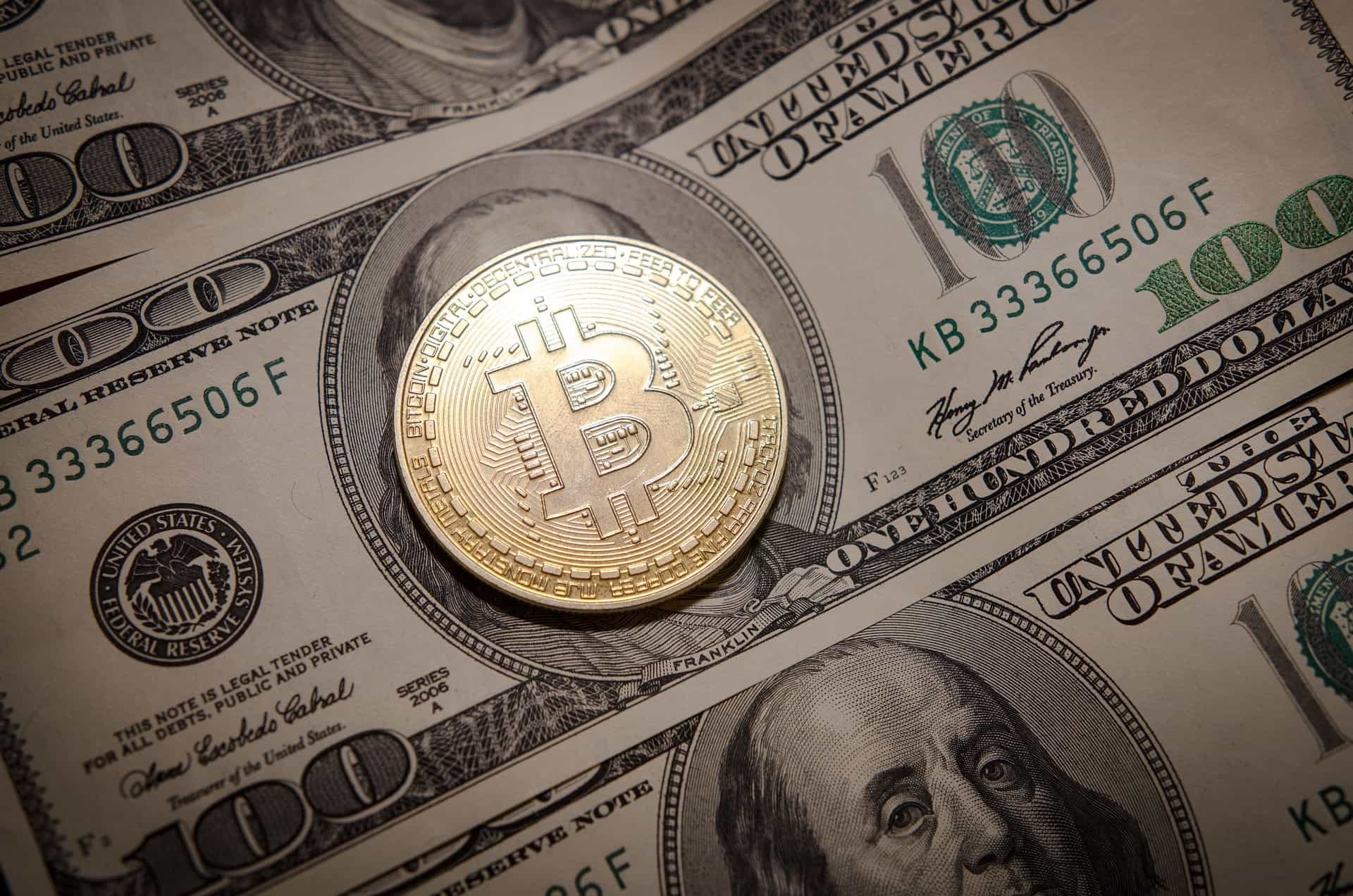 Sebuah bitcoin berada di atas uang kertas $100.