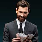 Ein Mann im Anzug hält mehrere Geldscheine in der Hand.