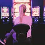 Junge Frau spielt in einer Spielothek vor einem Geldspielautomaten.