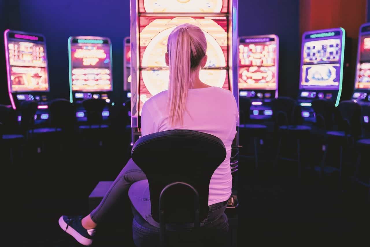 Wanita muda bermain di mesin slot di depan mesin slot.