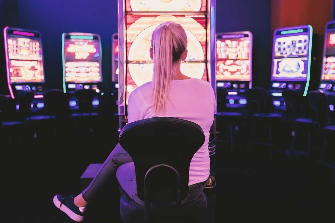 Junge Frau spielt in einer Spielothek vor einem Geldspielautomaten.