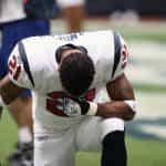 Ein Spieler der NFL steht auf einem Knie und beugt den Kopf nach vorne.