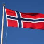 Auf einem Mast weht die norwegische Flagge im Wind.