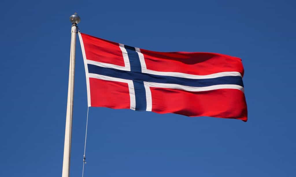 Bendera Norwegia berkibar tertiup angin di tiang.