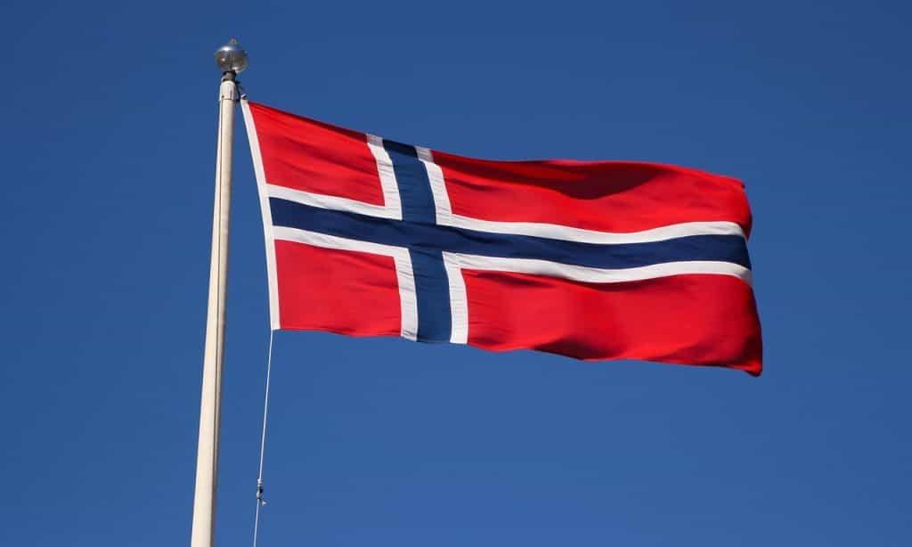 Auf einem Mast weht die norwegische Flagge im Wind.