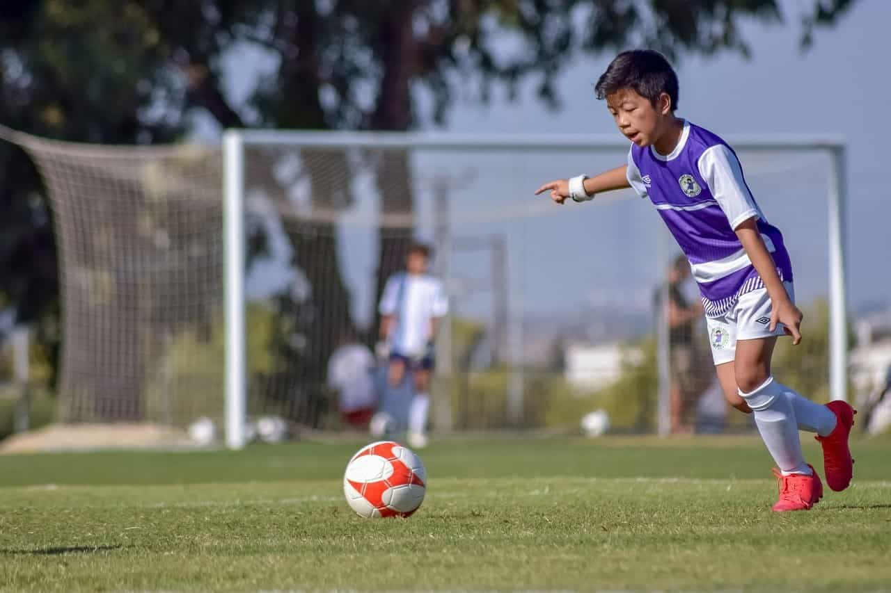 Zwei Kinder, die vereinsmäßig im Trikot Fußball spielen.