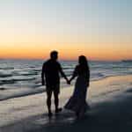 Photography of man and woman holding hands each other while walking beside seashore photo