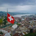 Schweizer Flagge vor einem Stadtpanorama